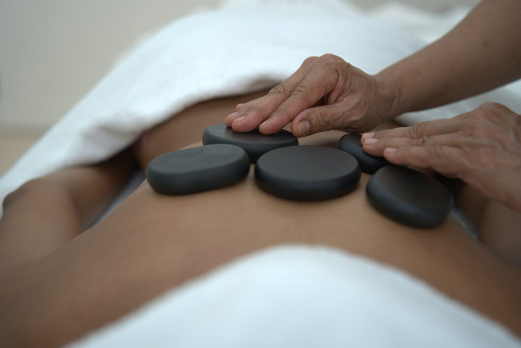 Empress Massage therapist placing hot cobalt stones on the back of a client during a hot stone massage in dubai.