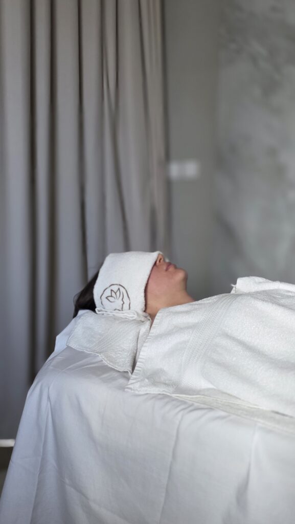 Client fully relaxed under fresh towels during a home massage