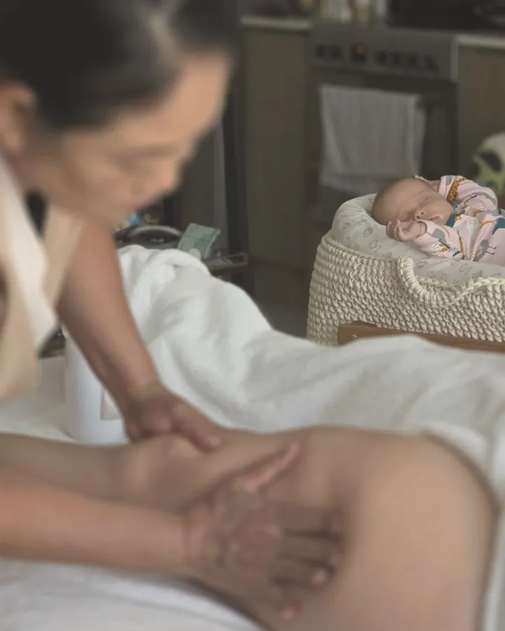 Postnatal massage for a new mother at home in Dubai while her baby sleeps nearby